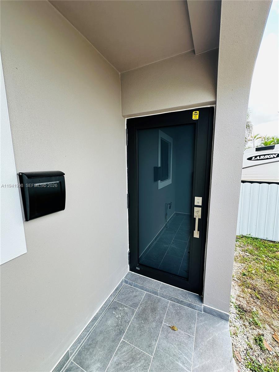 A black front door with frosted glass sits next to a black mailbox on a porch — 7157 W 19th Ct # 7157, Hialeah FL 33014, HIALEAH, FL