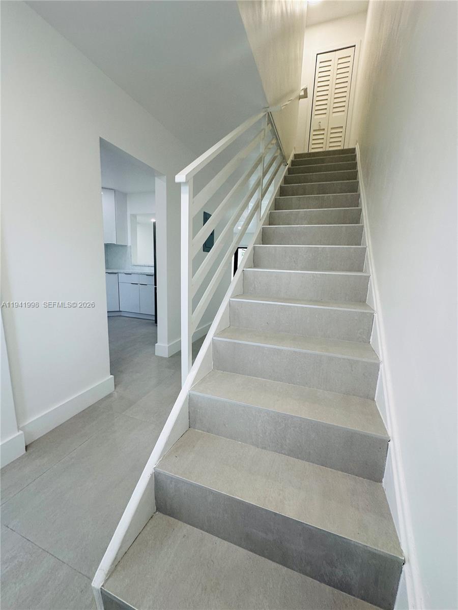 A staircase with gray tiled steps and a white railing leads to an upper floor — 7157 W 19th Ct # 7157, Hialeah FL 33014, HIALEAH, FL