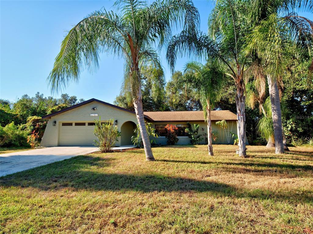 A single-story house with a garage and palm trees sits on a grassy lot — 2767 SALLY LANE, NORTH PORT, FL