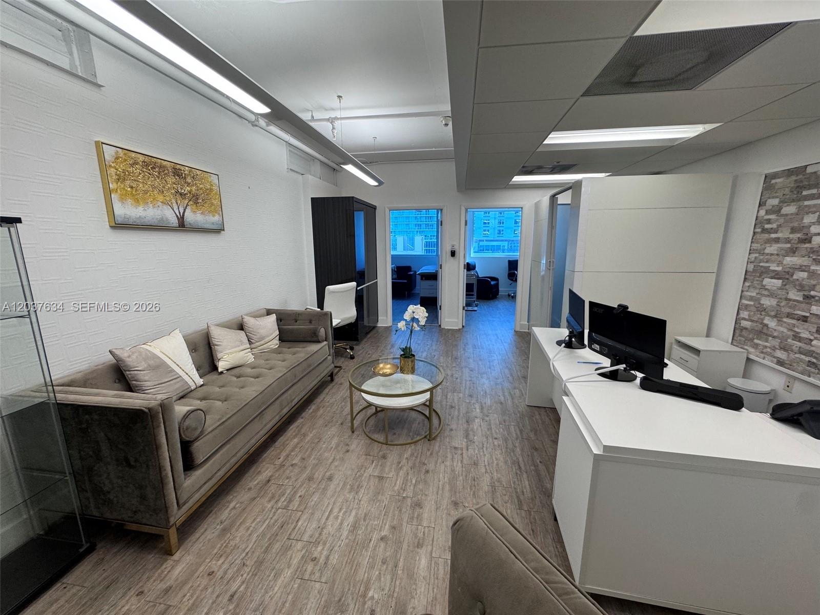 An office space features a tufted sofa, a white desk, and two doorways leading outside — 40 SW 13th St # 402, Miami FL 33130, MIAMI, FL