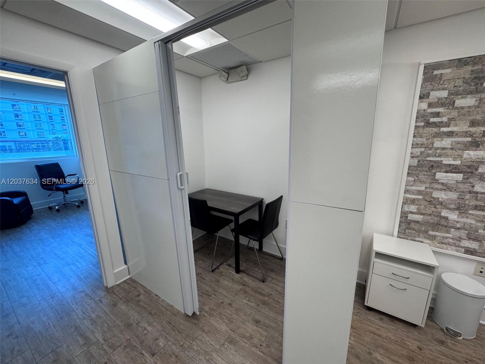 A small, enclosed office space features a dark table, two chairs, and white walls — 40 SW 13th St # 402, Miami FL 33130, MIAMI, FL