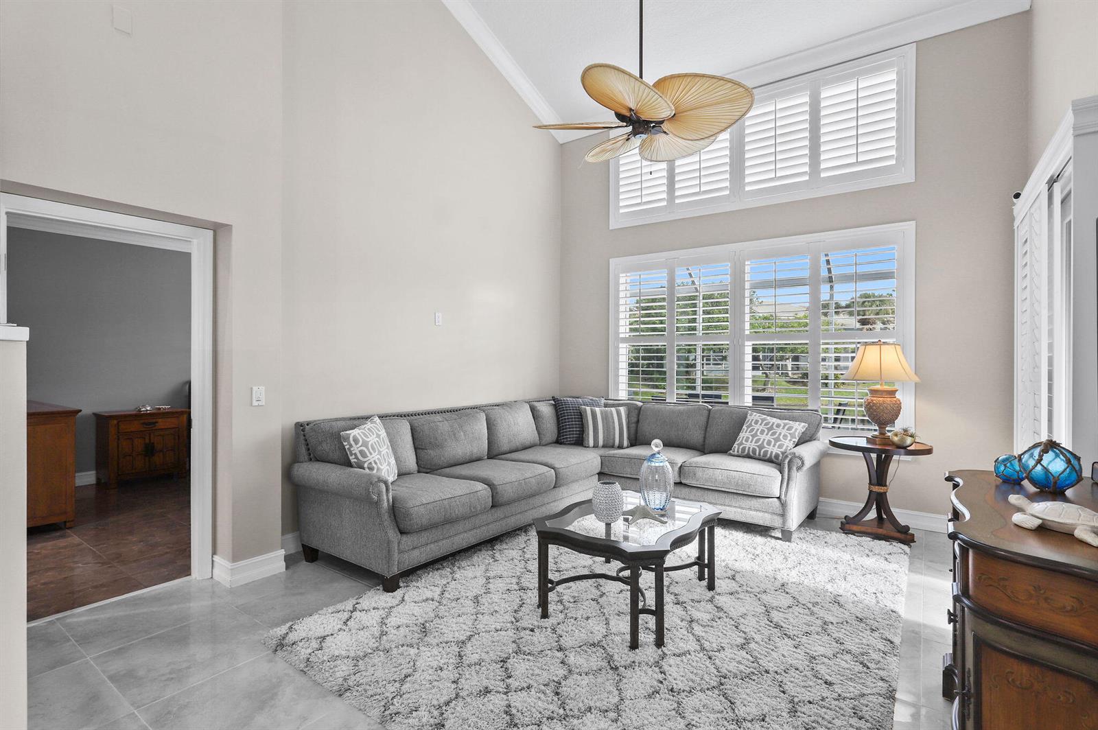 A living room features a grey sectional sofa, a patterned rug, and high vaulted ceilings — 2056 Windward Way, Jupiter FL 33477, JUPITER, FL
