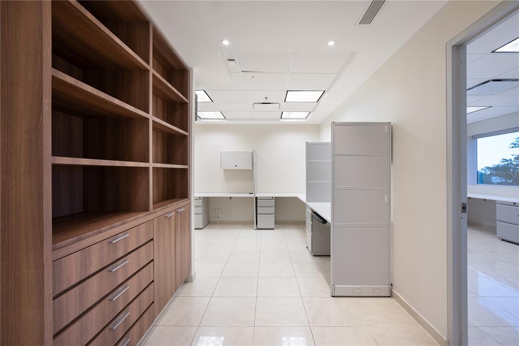 An office space features built-in wooden shelving, white tile flooring, and modular workstations — 90 CARR 165 SUITE 309 CENTRO INTERNACIONAL DE MERCADEO, GUAYNABO, PR