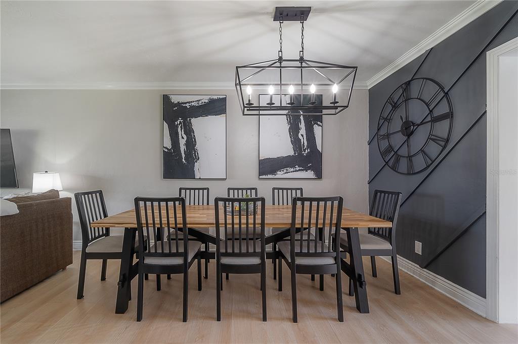 A dining room features a wooden table, black chairs, a modern chandelier, and a decorative clock — 2916 W COLLINS STREET, TAMPA, FL