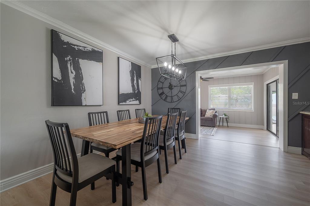 A dining room features a wooden table, black chairs, a chandelier, and a dark accent wall — 2916 W COLLINS STREET, TAMPA, FL