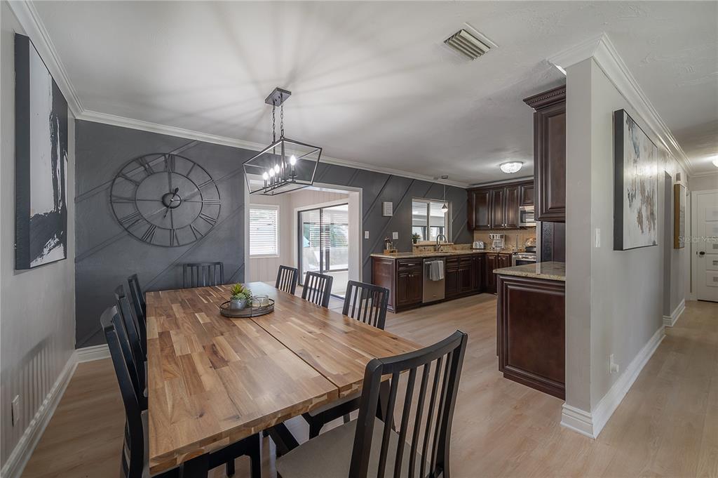 A dining area with a wood table and dark accent wall opens into a kitchen — 2916 W COLLINS STREET, TAMPA, FL
