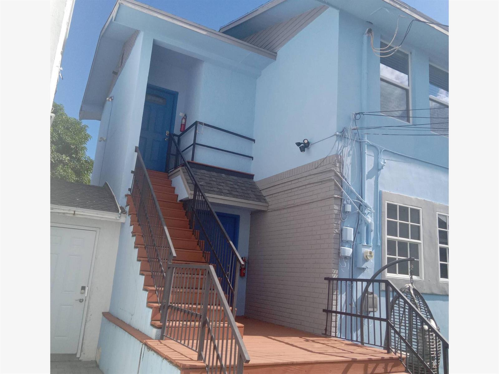 A blue building exterior features a set of stairs leading to a patio area — 816 9th Street, West Palm Beach FL 33401, WEST PALM BEACH, FL