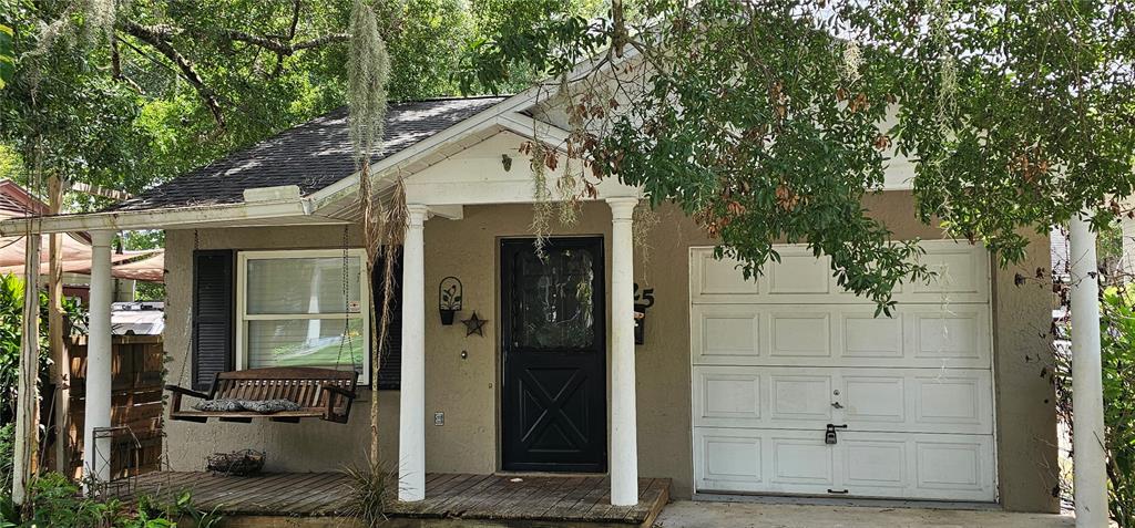 A small house with a wooden porch, a hanging bench, and an attached white garage — 25 N GLENWOOD AVENUE, ORLANDO, FL