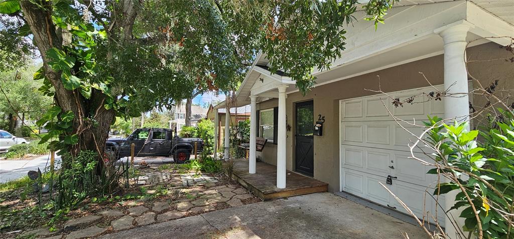A house exterior features a wooden porch, white columns, a garage door, and a large tree — 25 N GLENWOOD AVENUE, ORLANDO, FL