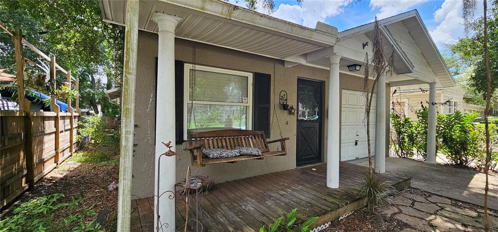 A wooden porch with a hanging bench and white columns sits in front of a house — 25 N GLENWOOD AVENUE, ORLANDO, FL