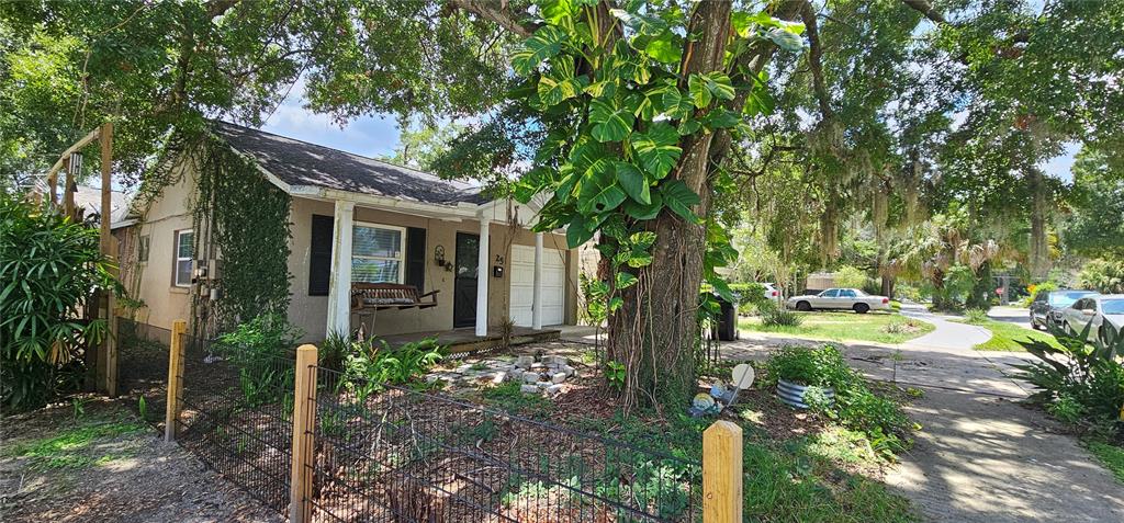 A small, single-story house with a porch and a large tree in the front yard — 25 N GLENWOOD AVENUE, ORLANDO, FL