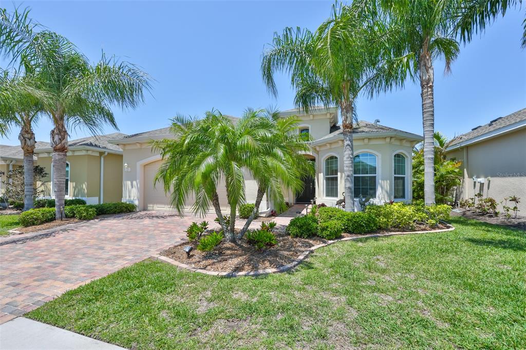 A single-story house with a paved driveway, palm trees, and a landscaped front yard — 1809 PACIFIC DUNES DRIVE, SUN CITY CENTER, FL
