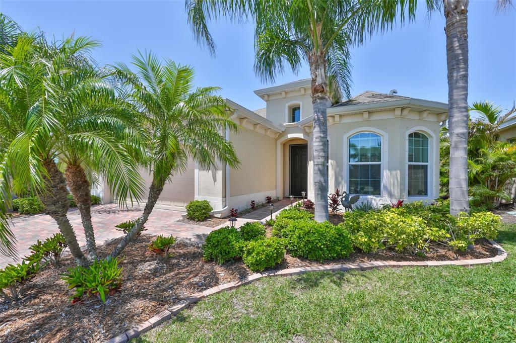A single-story house with a beige stucco exterior, arched windows, and a landscaped front yard — 1809 PACIFIC DUNES DRIVE, SUN CITY CENTER, FL
