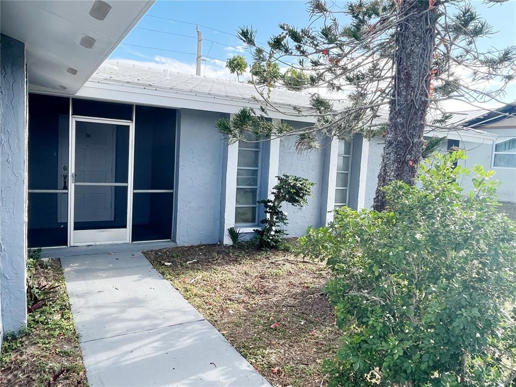 A light blue house exterior features a screened front entryway and a concrete walkway — 75 ANNAPOLIS LANE, ROTONDA WEST, FL