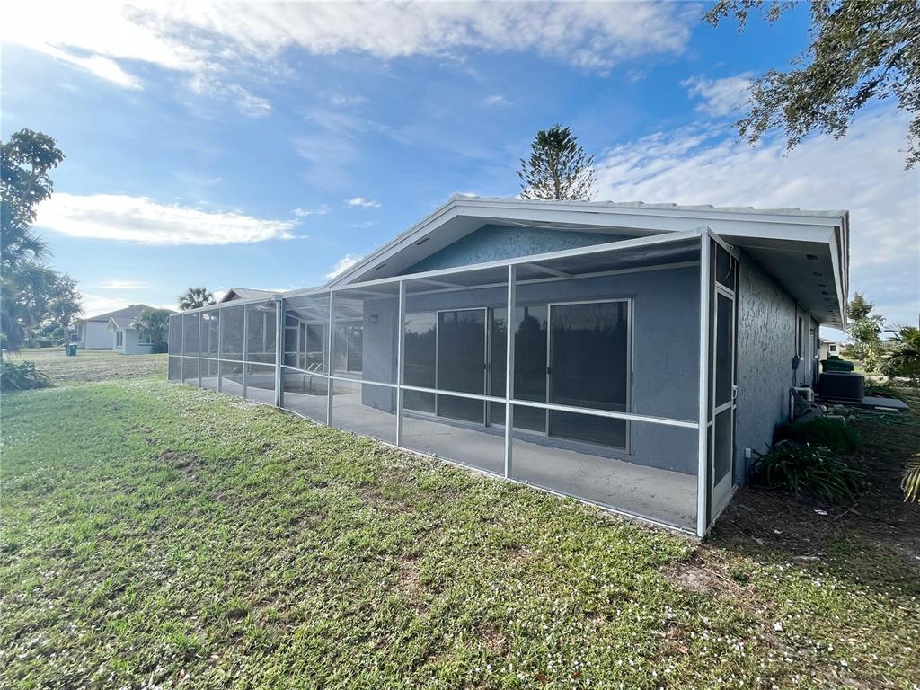 The exterior of a house features a screened-in pool enclosure and a concrete patio — 75 ANNAPOLIS LANE, ROTONDA WEST, FL