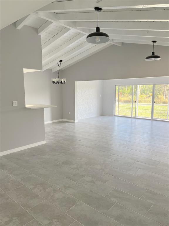 A bright, open-concept living area features gray tile flooring, a vaulted ceiling, and sliding glass doors — 75 ANNAPOLIS LANE, ROTONDA WEST, FL