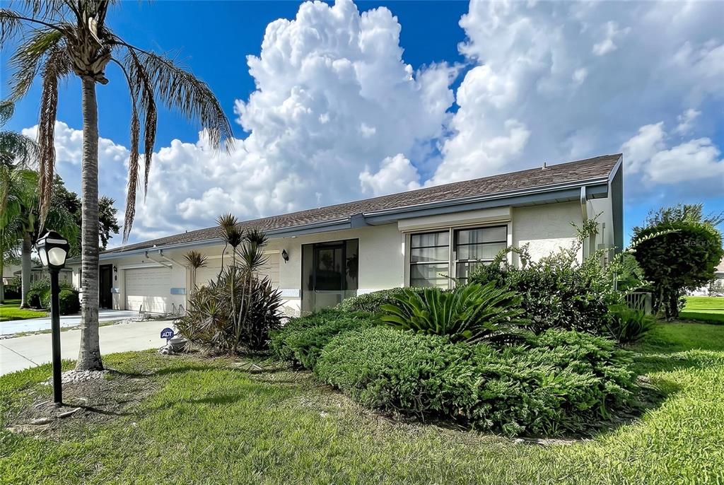 A single-story house with a beige stucco exterior, a shingled roof, and landscaped front yard — 2110 S HALCYON DRIVE UNIT 456, SUN CITY CENTER, FL