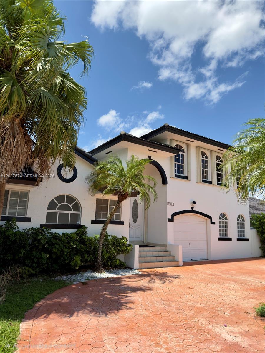 A two-story white house features a tiled roof, arched windows, and a paved driveway — 14291 SW 34th St, Miami FL 33175, MIAMI, FL