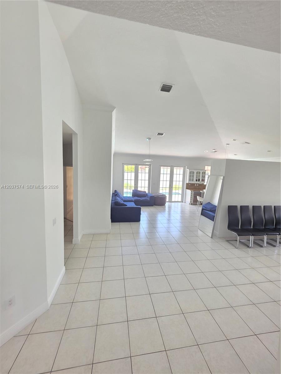 A spacious open-concept living area features white tile floors, a kitchen, and modern lighting — 14291 SW 34th St, Miami FL 33175, MIAMI, FL
