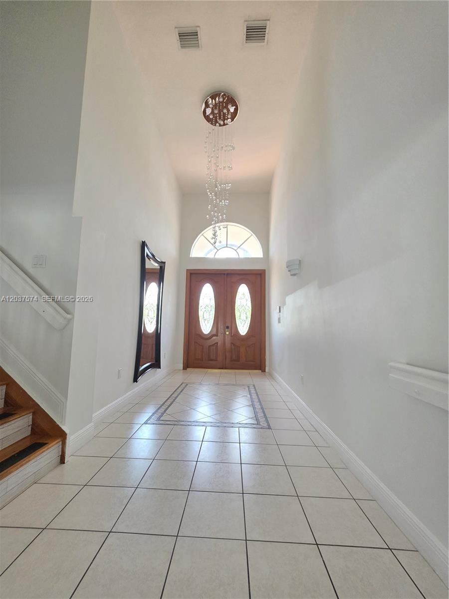 A bright kitchen features white cabinets, granite countertops, a central island, and tiled flooring — 14291 SW 34th St, Miami FL 33175, MIAMI, FL