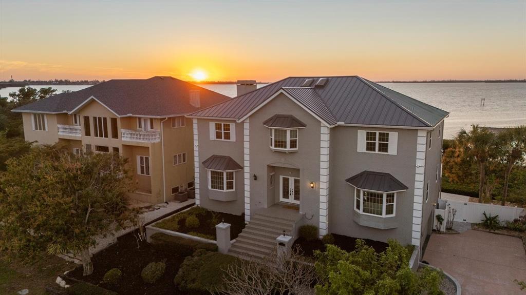 An aerial view of a two-story gray house with a metal roof at sunset — 3308 PALMA SOLA BOULEVARD, BRADENTON, FL