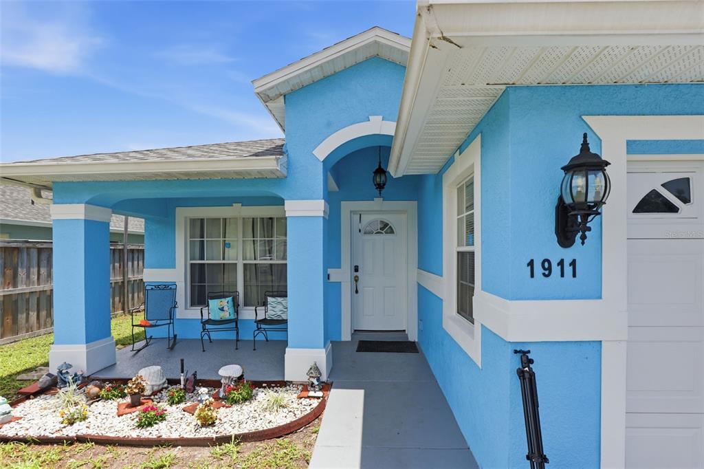 A bright blue house exterior features a covered front porch, white trim, and a walkway — 1911 S GADSEN BOULEVARD, ORLANDO, FL