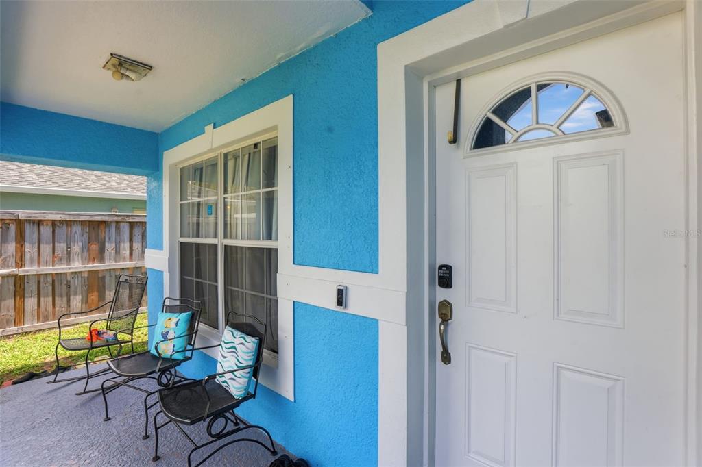 A bright blue exterior wall with a white front door and two metal patio chairs — 1911 S GADSEN BOULEVARD, ORLANDO, FL