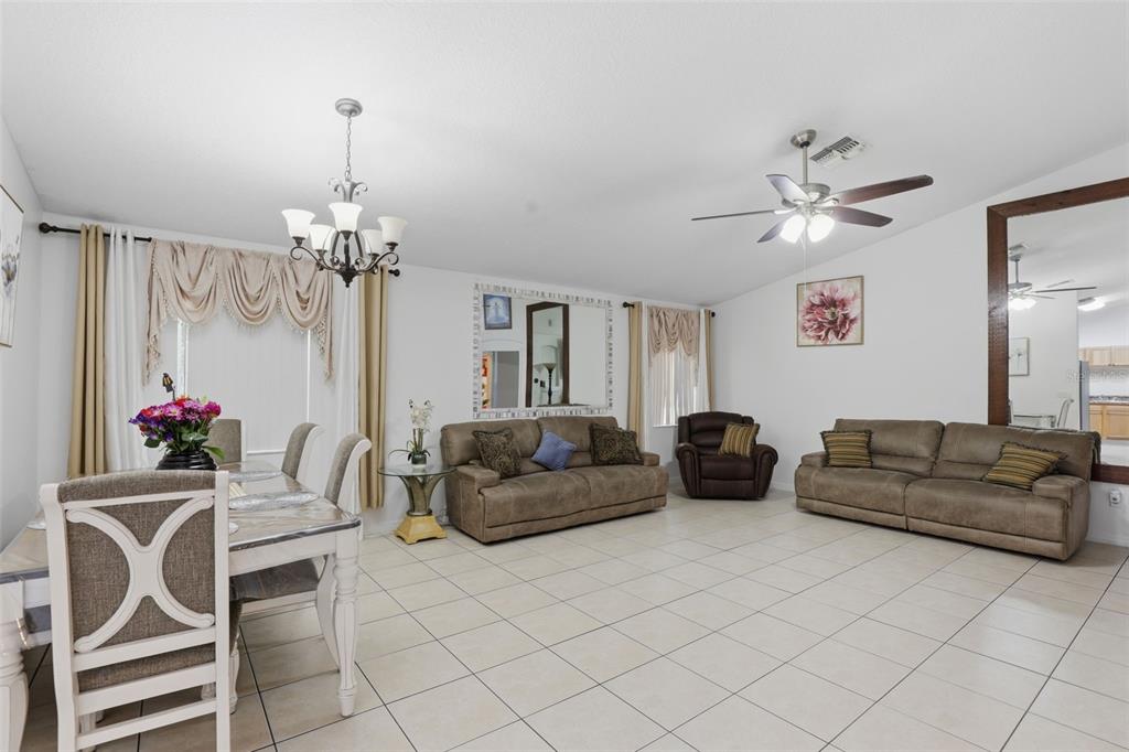 A living and dining room with tiled floors, two sofas, a recliner, and a chandelier — 1911 S GADSEN BOULEVARD, ORLANDO, FL