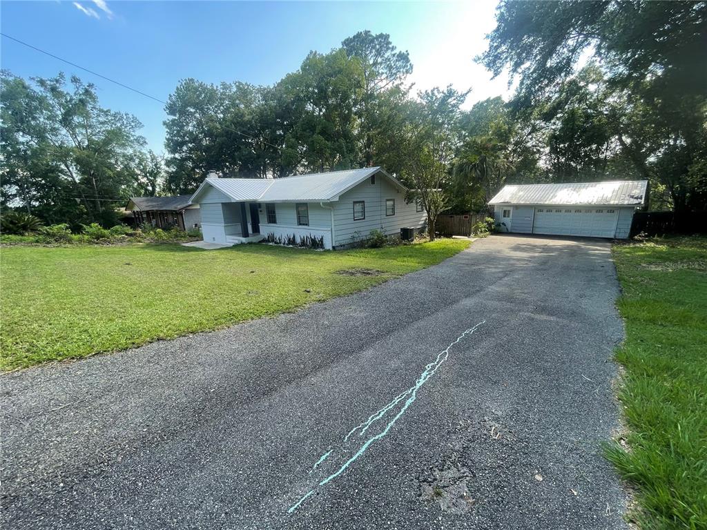 A light-colored house with a metal roof and a detached garage sit on a lot — 1108 CUERNO STREET, TALLAHASSEE, FL