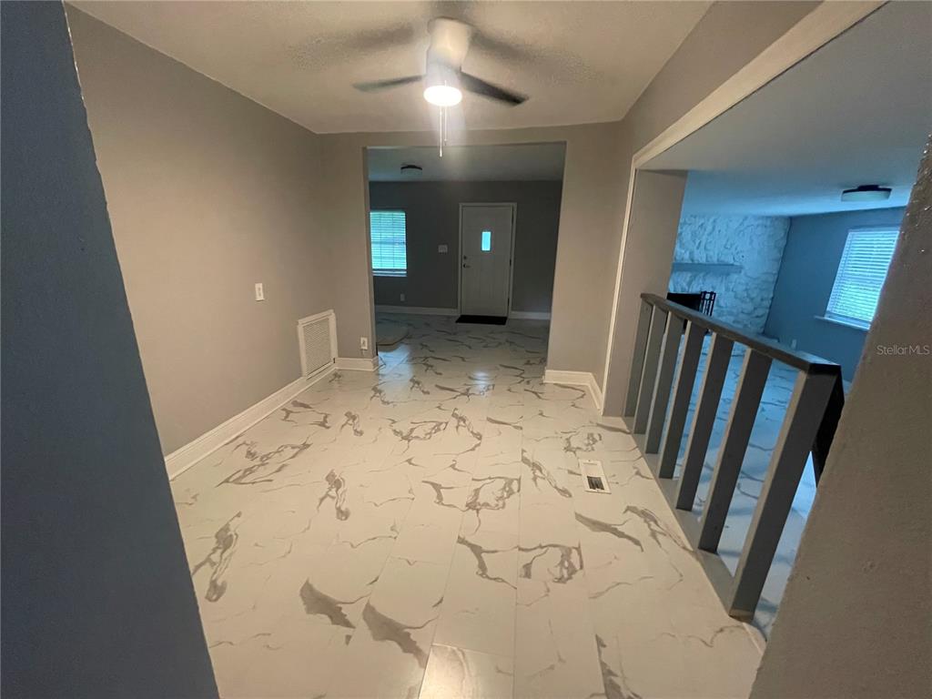 A room with marble-patterned tile flooring, a ceiling fan, and a staircase with railings — 1108 CUERNO STREET, TALLAHASSEE, FL