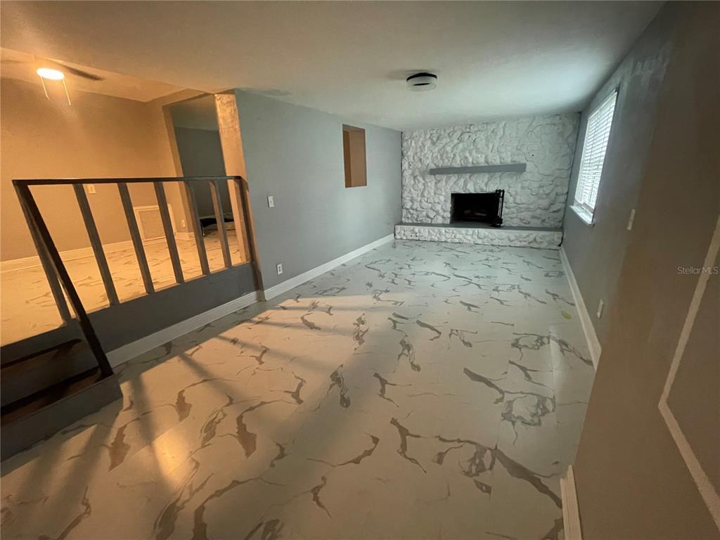 A living room features a white stone fireplace, gray walls, and marble-patterned flooring — 1108 CUERNO STREET, TALLAHASSEE, FL