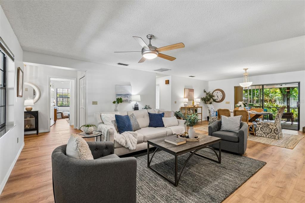 A living room features a ceiling fan, gray armchairs, a sofa, and wood-look flooring — 16509 ROUND OAK DRIVE, TAMPA, FL