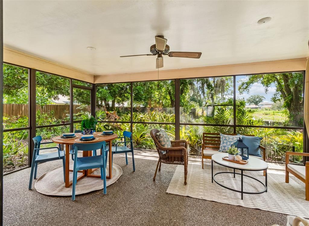 A screened-in patio features a dining set, lounge seating, and views of lush outdoor greenery — 16509 ROUND OAK DRIVE, TAMPA, FL