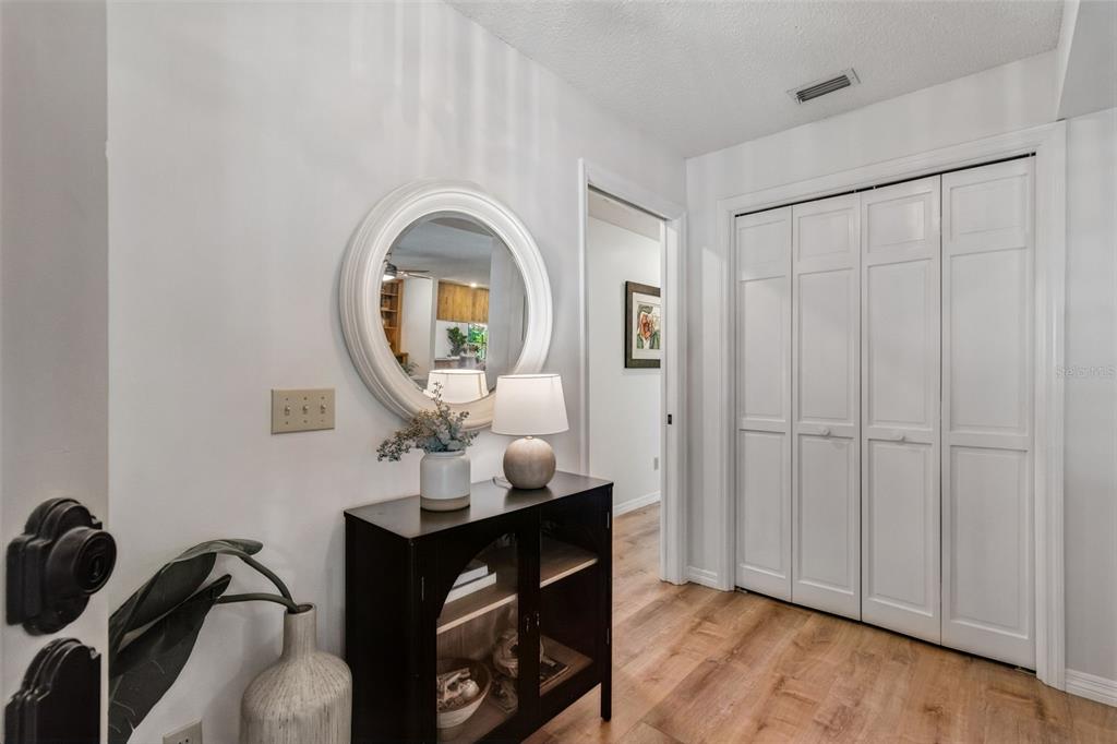 An entryway features a dark console table, a round mirror, and white bifold closet doors — 16509 ROUND OAK DRIVE, TAMPA, FL
