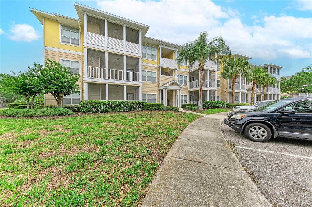 A three-story apartment building with screened balconies, yellow siding, and a paved walkway — 4802 51ST STREET W UNIT 1311, BRADENTON, FL
