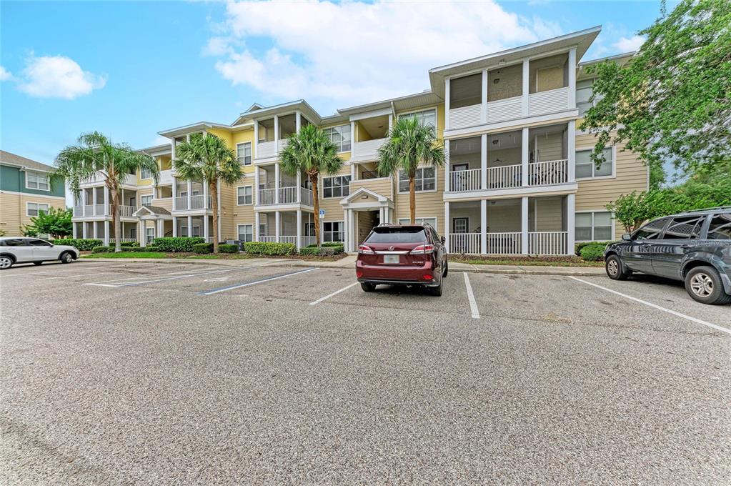 A multi-story apartment building with screened balconies and a parking lot in the foreground — 4802 51ST STREET W UNIT 1311, BRADENTON, FL