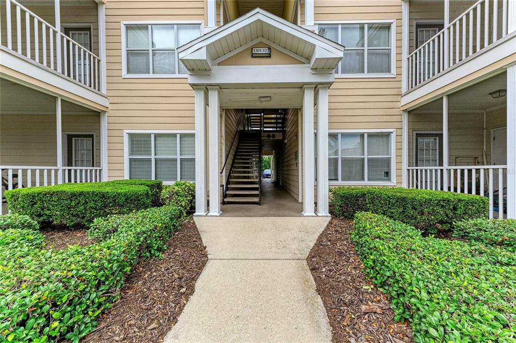 A concrete walkway leads to the entrance of a multi-story apartment building with stairs — 4802 51ST STREET W UNIT 1311, BRADENTON, FL