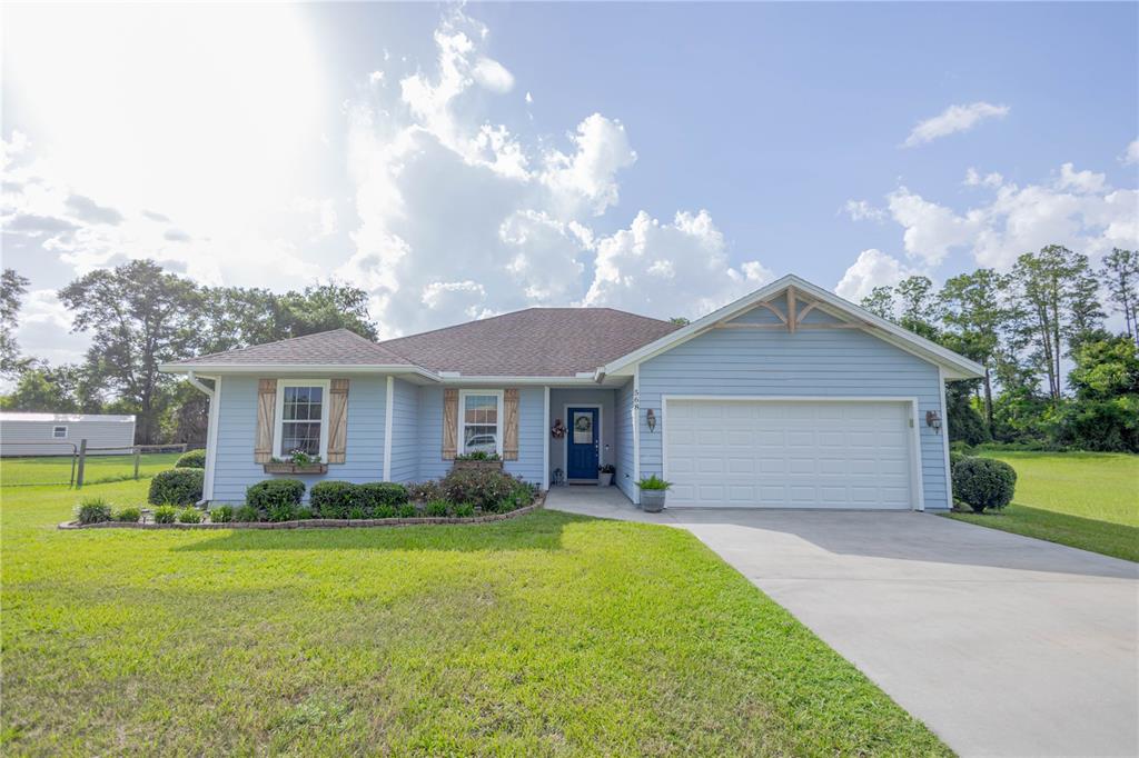 A light blue single-story house features a two-car garage and a front lawn — 568 SW GERALD CONNER DRIVE, LAKE CITY, FL