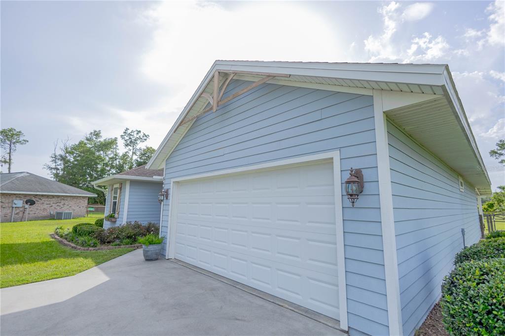 A light blue house exterior features a white garage door and a concrete driveway — 568 SW GERALD CONNER DRIVE, LAKE CITY, FL