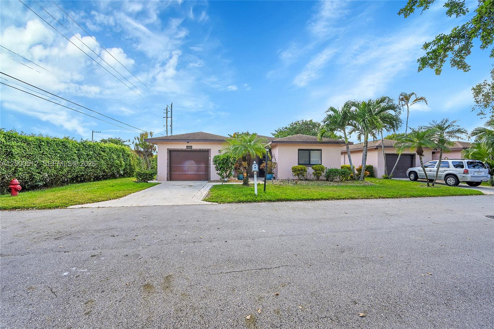 A single-story house with a garage, driveway, and palm trees sits under a blue sky — 14664 Bonaire Boulevard # 1, Delray Beach FL 33446, DELRAY BEACH, FL