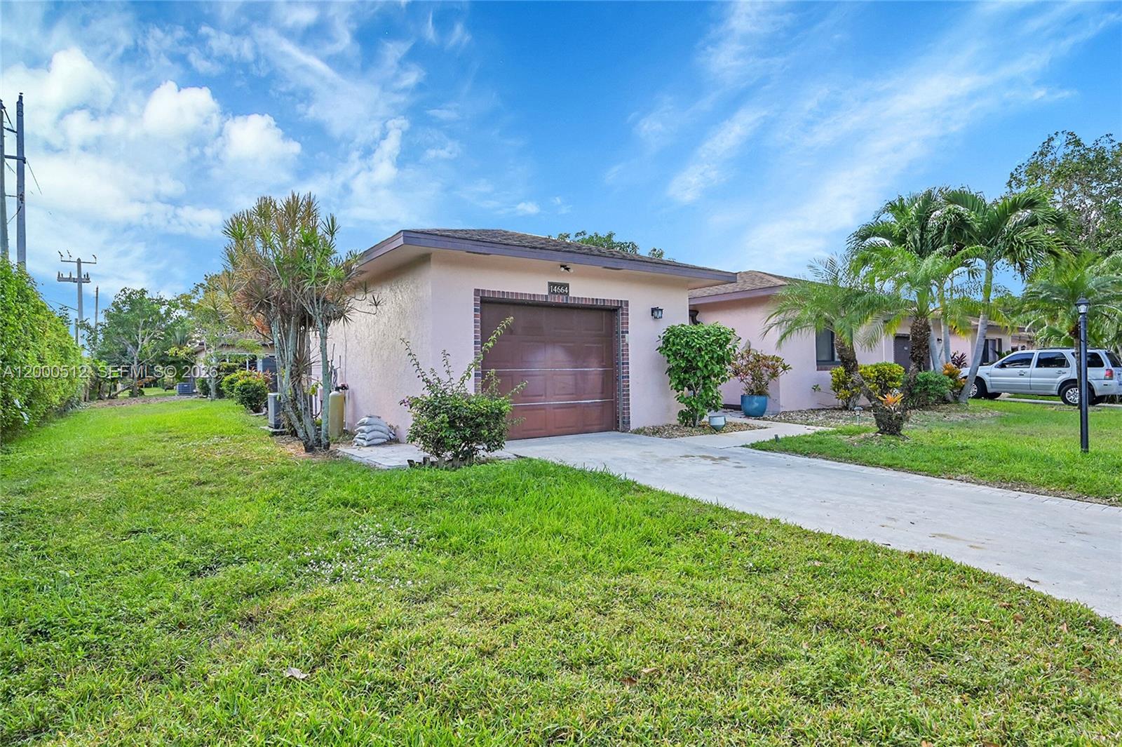 A single-story pink house with a brown garage door and a concrete driveway — 14664 Bonaire Boulevard # 1, Delray Beach FL 33446, DELRAY BEACH, FL