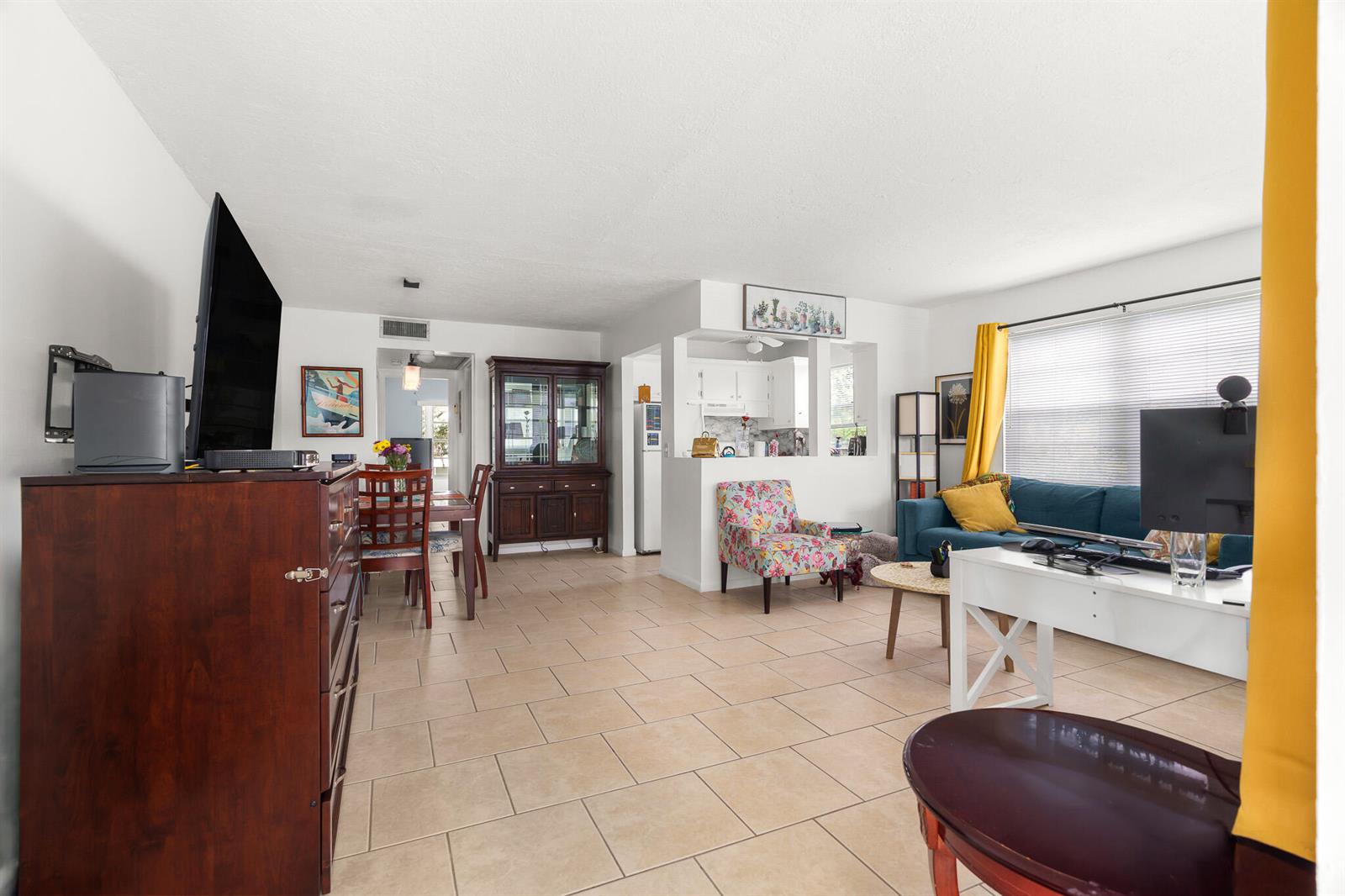 A living room with tile floors, a blue sofa, a floral armchair, and a dining area — 347 Windsor O, West Palm Beach FL 33417, WEST PALM BEACH, FL