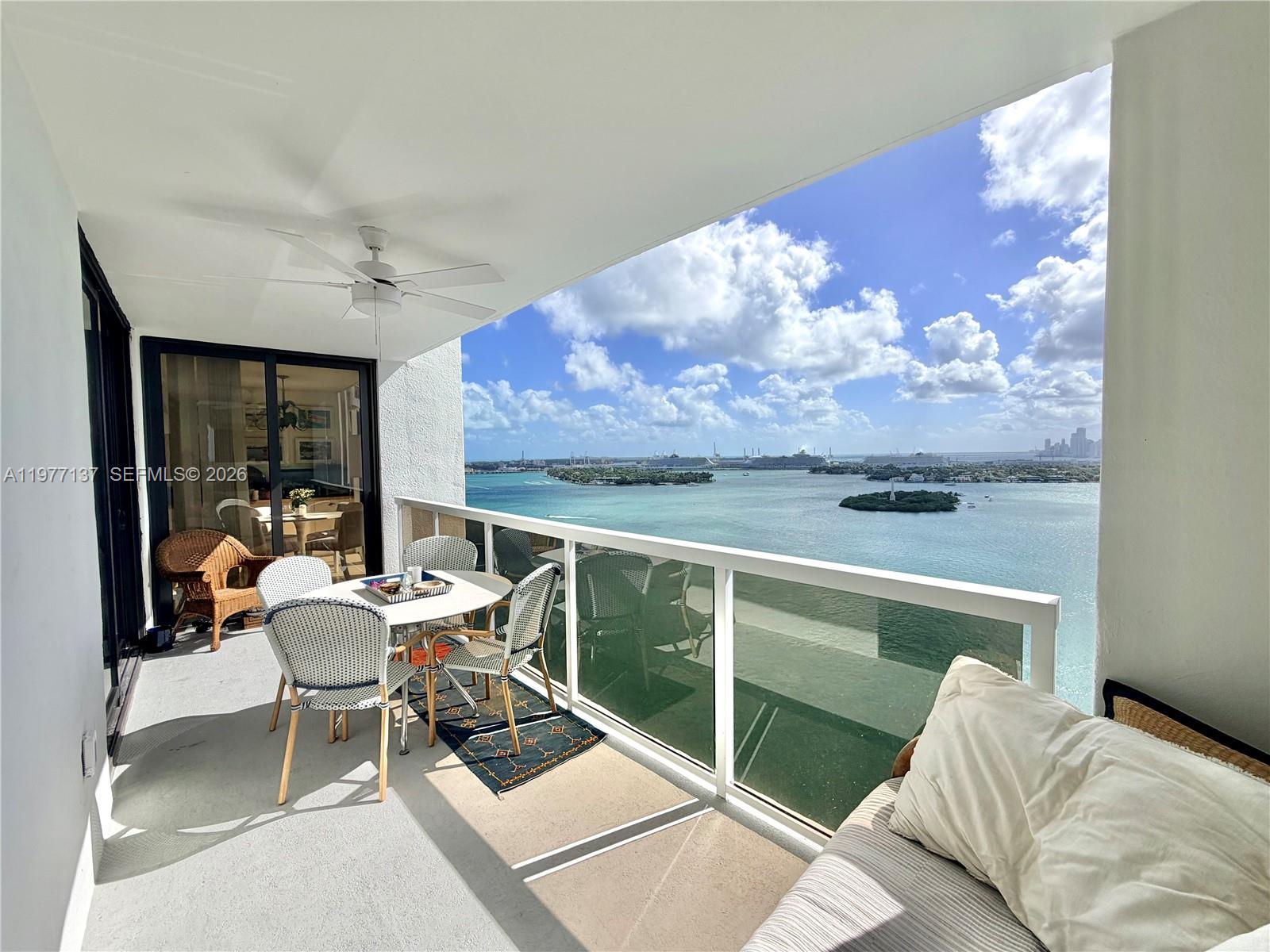 A balcony with outdoor furniture overlooks a bay with islands and a distant city skyline — 9 Island Ave # 2304, Miami Beach FL 33139, MIAMI BEACH, FL
