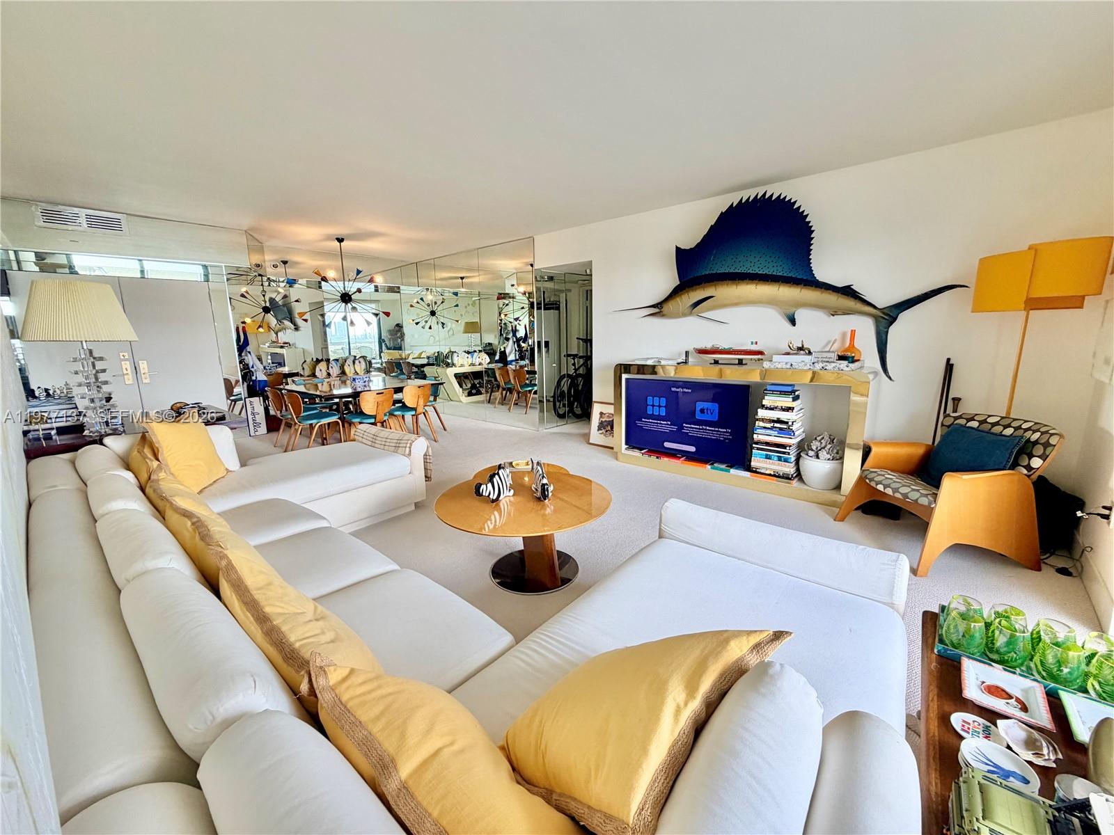A living room features a white sectional sofa, a round coffee table, and a large fish — 9 Island Ave # 2304, Miami Beach FL 33139, MIAMI BEACH, FL