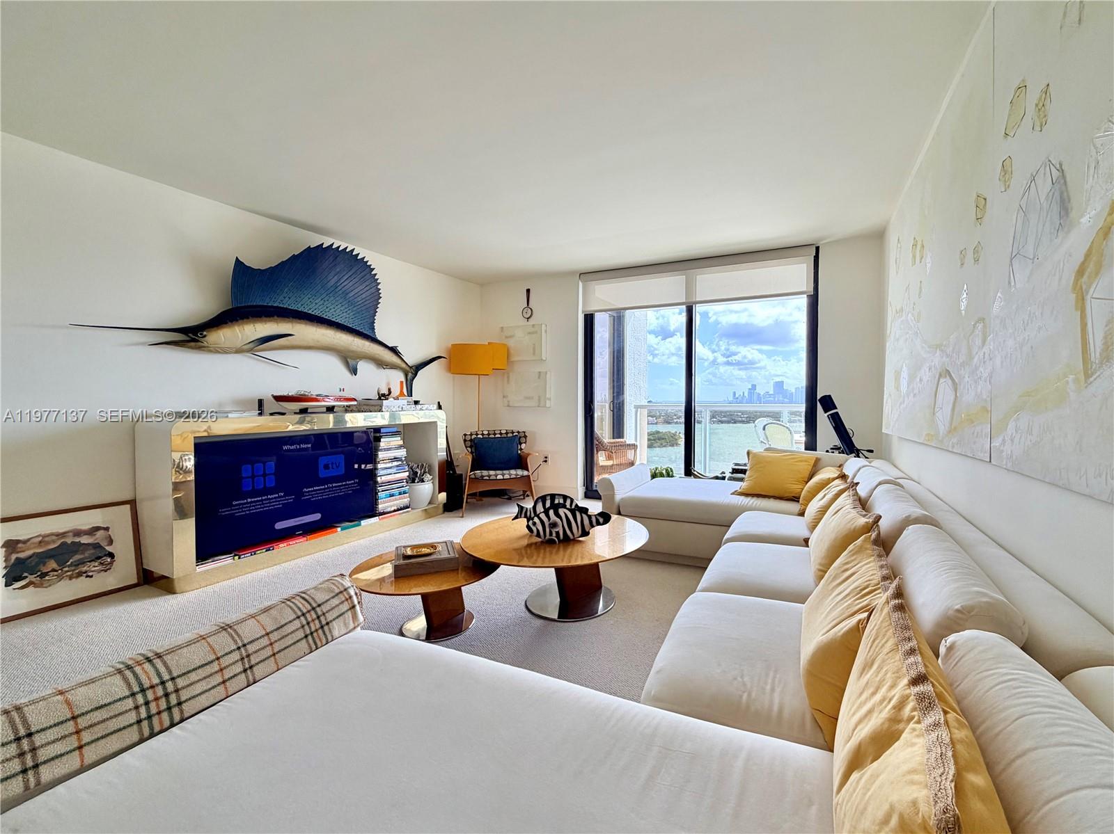 A living room features a large sailfish wall mount, a gold media console, and balcony views — 9 Island Ave # 2304, Miami Beach FL 33139, MIAMI BEACH, FL