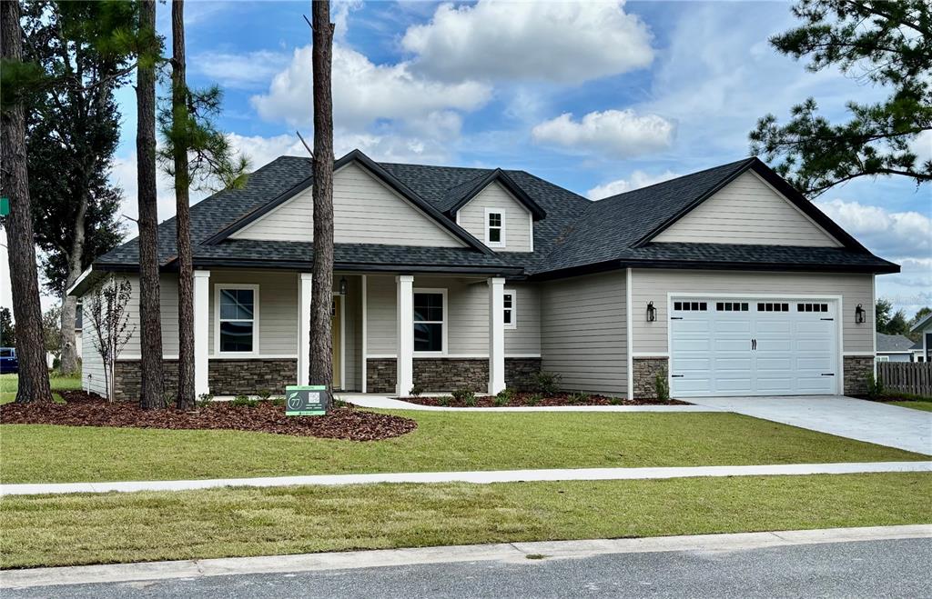 A single-story house with light gray siding, stone accents, a dark roof, and a garage — 20488 NW 160TH LANE, HIGH SPRINGS, FL