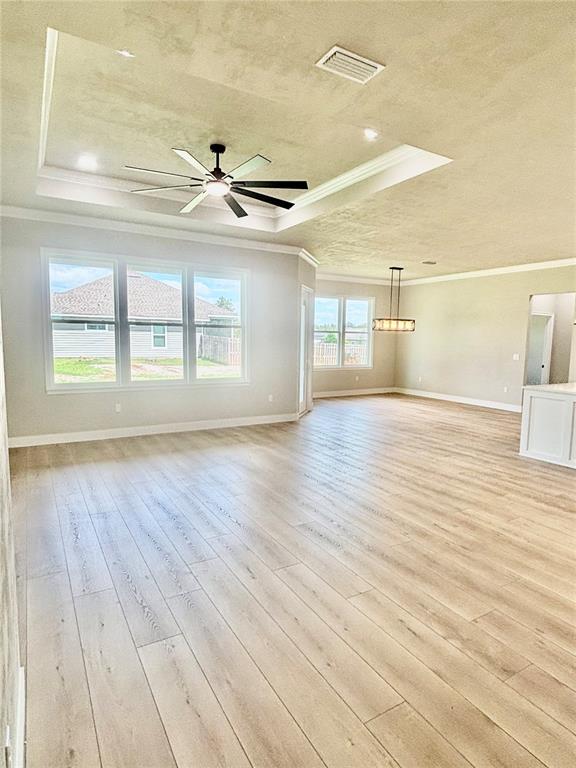 A spacious living room features light wood flooring, a tray ceiling with a fan, and windows — 20488 NW 160TH LANE, HIGH SPRINGS, FL