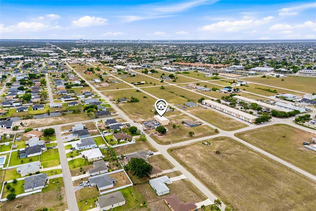 An aerial view shows a commercial building surrounded by residential houses and vacant land — 1010 NE 9TH STREET UNIT A, CAPE CORAL, FL