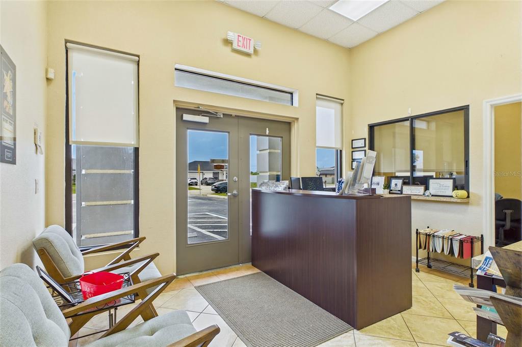 A reception area features a dark wood desk, two armchairs, and a double glass door — 1010 NE 9TH STREET UNIT A, CAPE CORAL, FL