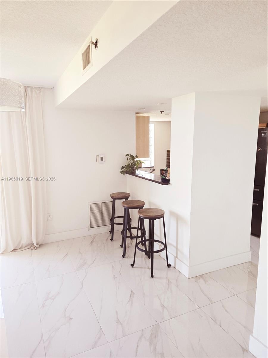 A kitchen breakfast bar with three stools sits on a white tiled floor — 1650 Coral Way # 702, Miami FL 33145, MIAMI, FL